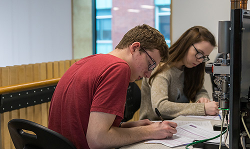 Male and female student working at a computer
