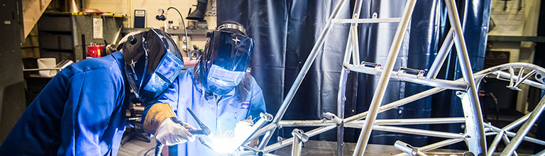 Two female students welding a frame